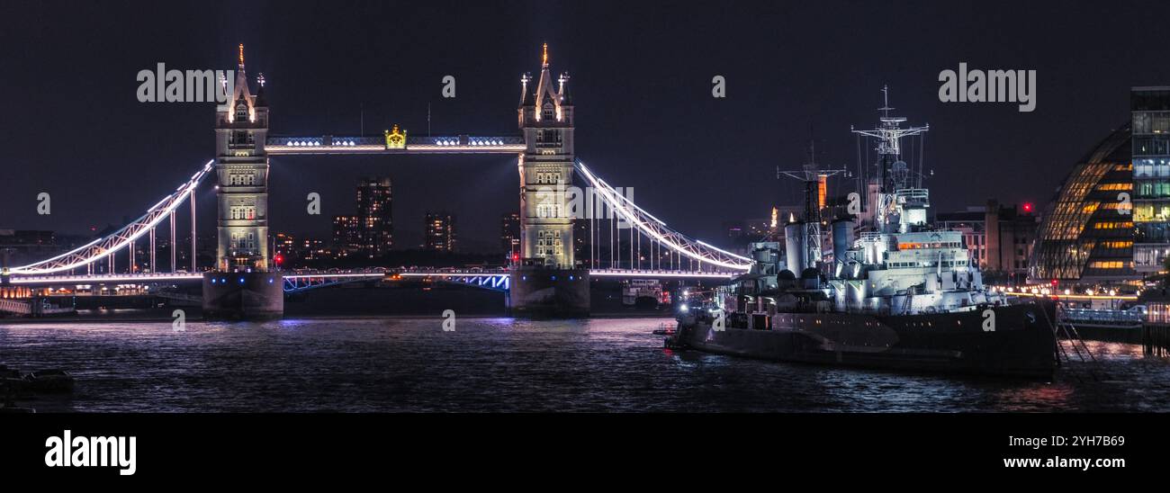 L'iconico Tower Bridge e la HMS Belfast illuminati di notte a Londra Foto Stock