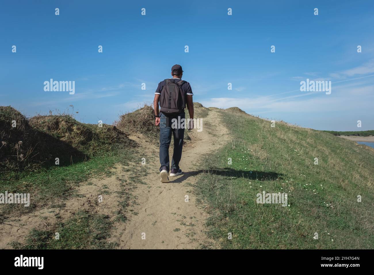 Uomo che arrampica con lo zaino su una collina in una giornata di sole. Uomo in vacanza che fa attività all'aperto. Escursioni sulla montagna. Attività all'aperto, Vlore. Viaggiare Foto Stock