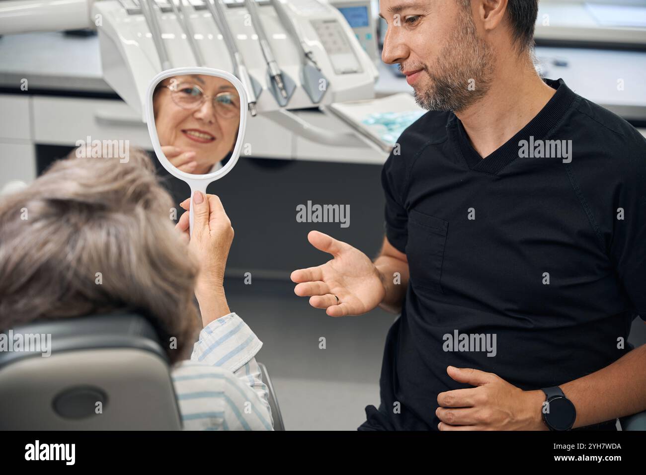 Signora in uno studio odontoiatrico con lo specchio in mano Foto Stock