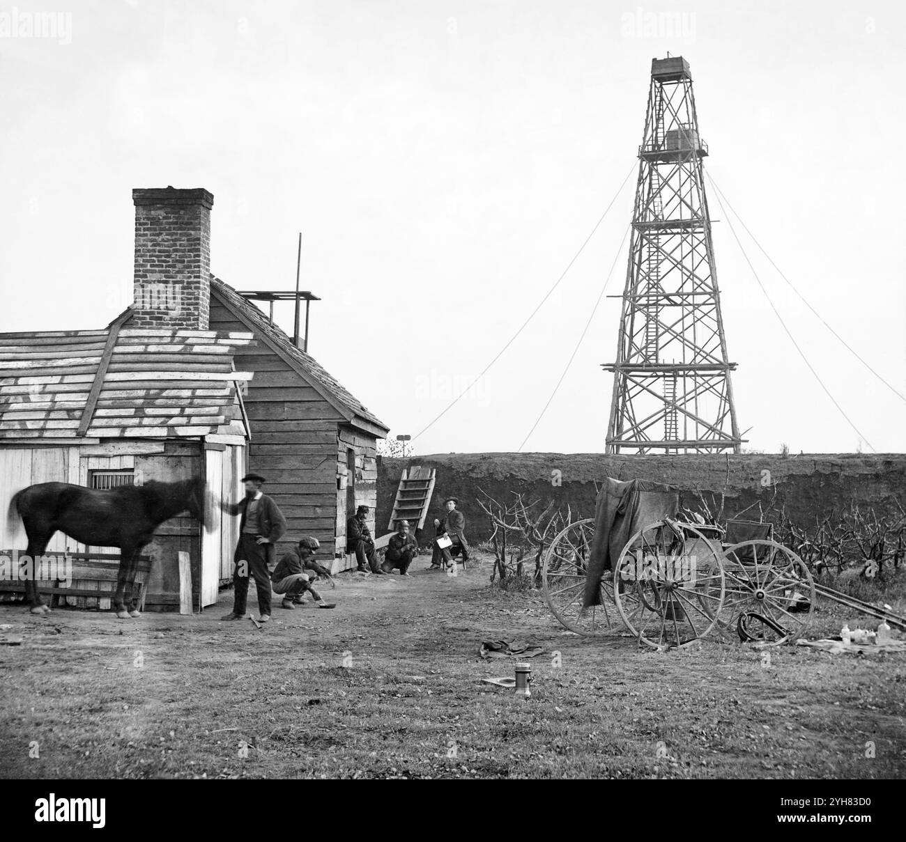 Un fotografo in residenza sta con il suo cavallo. Carrello fotografico visibile a destra. Preso alla torre di segnalazione di Butler, una stazione del Signal Corps, a Point Rocks, Appomatox River, Bermuda Hundred, Virginia, 1864. un gruppo di ufficiali in uniforme è visibile sullo sfondo. Mostra un uomo afroamericano che sta accovacciando insieme al Signal Corps. Fotografia dal principale teatro di guerra orientale, l'Armata del James, giugno 1864-aprile 1865. Foto Stock