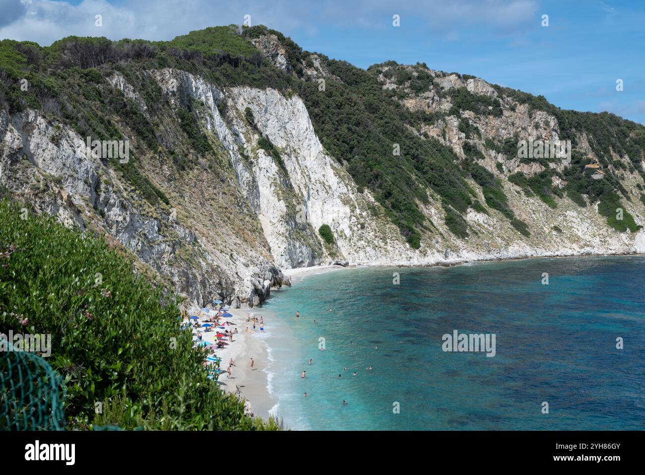 Spiaggia di Sansone all'Isola d'Elba in estate, con lettini e ombrellone con tanti bagnanti in riva al mare e nuoto Foto Stock