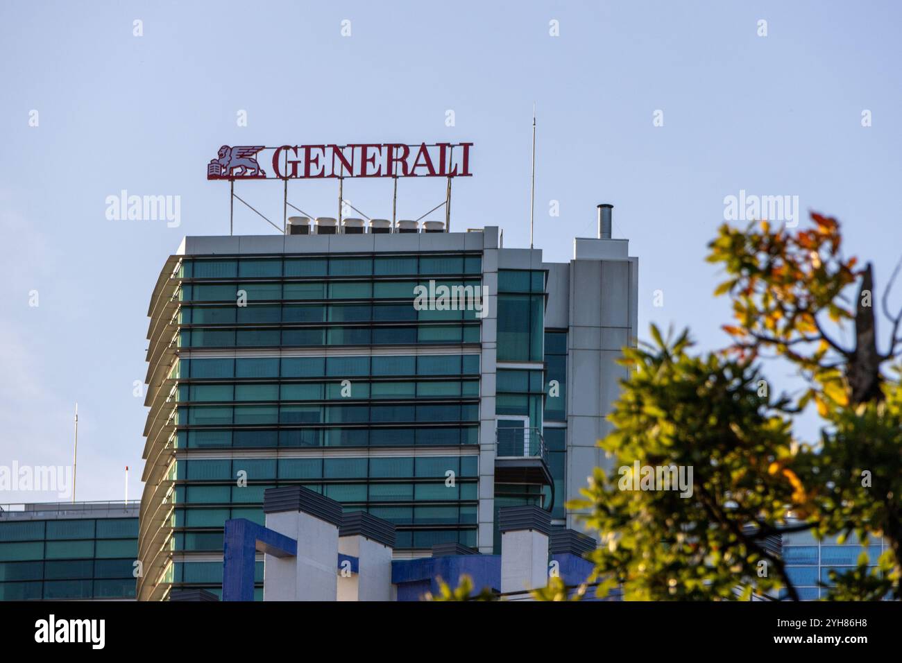 La torre generali si erge su un cielo azzurro e limpido, con rami d'albero che aggiungono un tocco di natura al paesaggio urbano Foto Stock