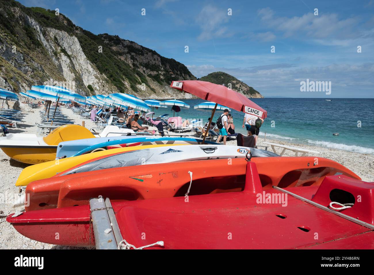 Tavole da paddle multicolore uscite dalle acque blu della spiaggia di Sansone nell'isola d'Elba (Italia) in estate Foto Stock