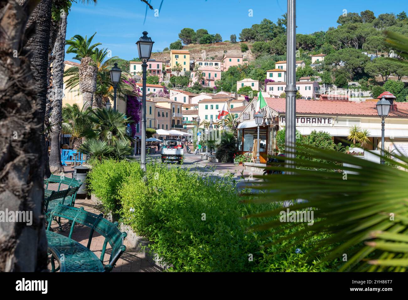 Una strada con ristorante nel centro di Porto Azzurro all'Isola d'Elba in Toscana. Ci sono un ristorante, luci stradali e un parco con Foto Stock