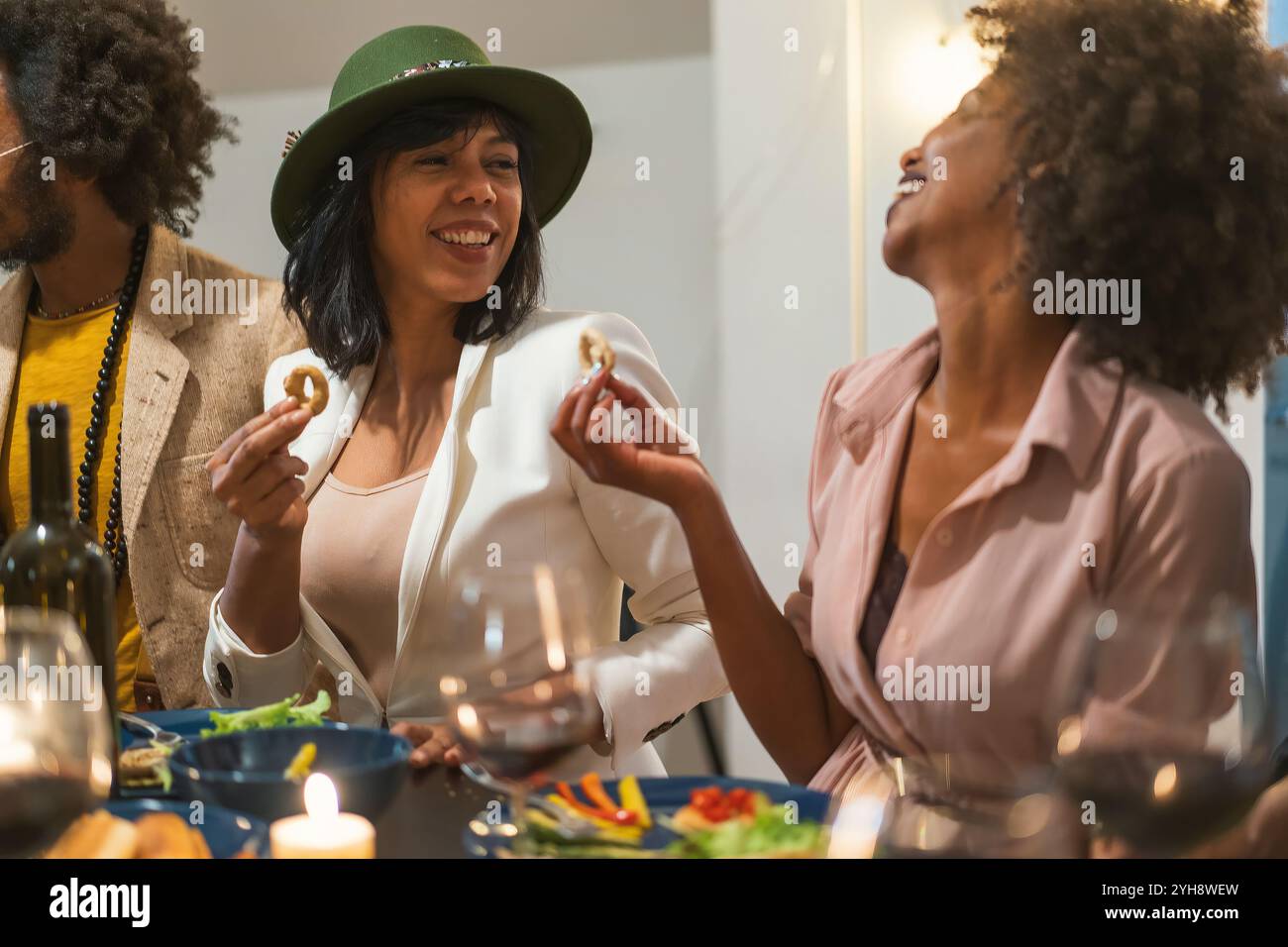 Gruppi multiculturali di amici che condividono antipasti e ridono durante un'elegante cena con atmosfera a lume di candela Foto Stock