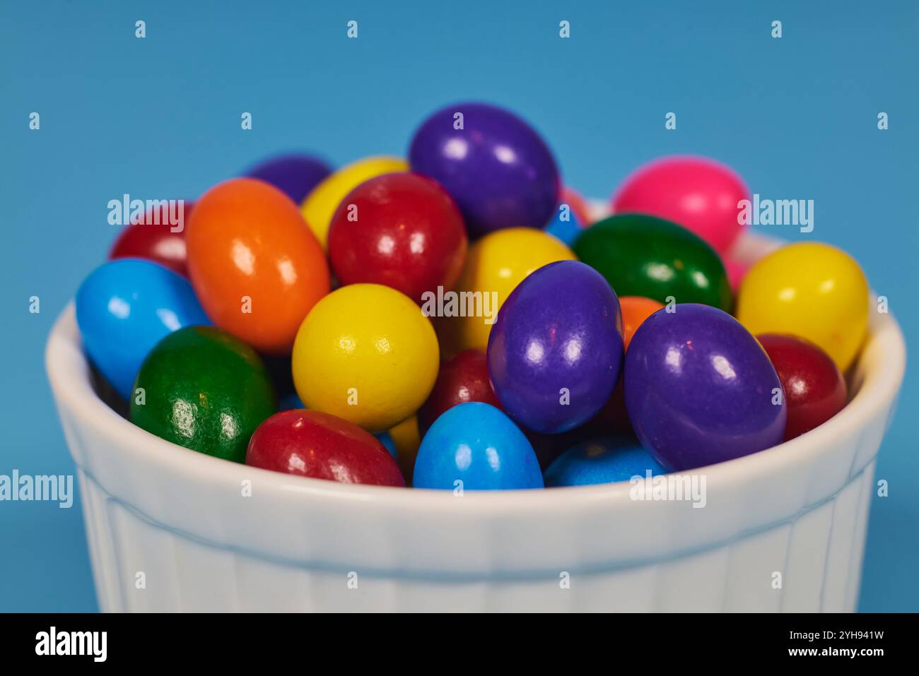 Palle di gomma da masticare di diversi colori in contenitori lucidi in terracotta con uno sfondo colorato omogeneo per il posizionamento del testo Foto Stock