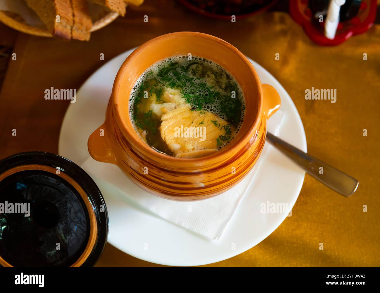 Appetitosa zuppa di orecchie con erbe in pentola di argilla Foto Stock