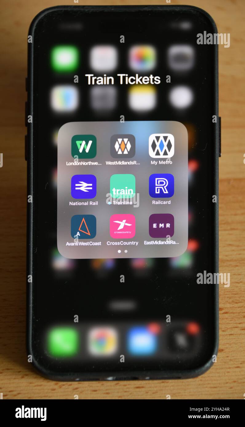 Smartphone del Regno Unito sul tavolo con le applicazioni dei biglietti ferroviari in una cartella per le società operative dei treni, National Rail, Railcard e Trainline.com Foto Stock