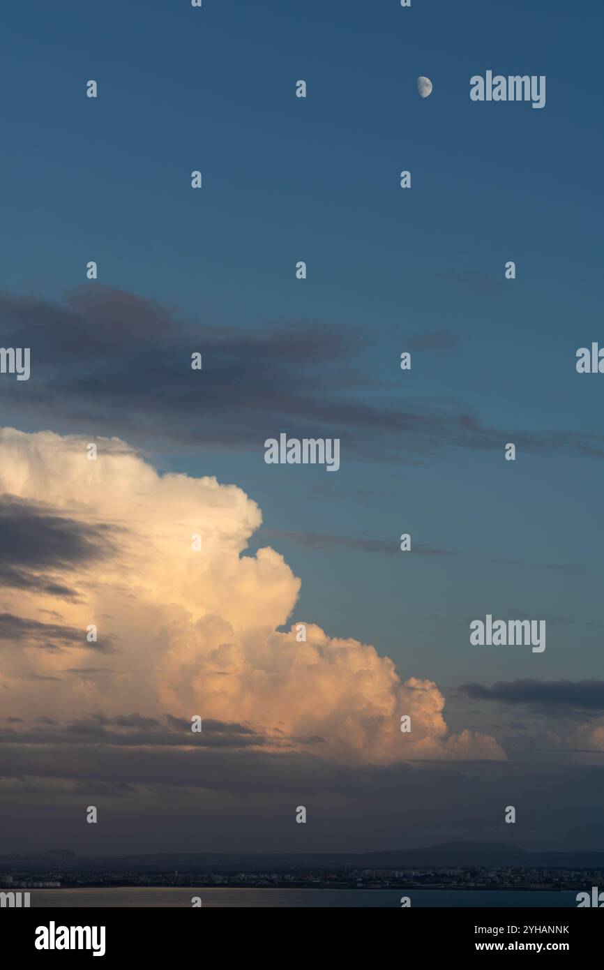 Grandi nuvole al tramonto, la luna in un cielo blu e il fiume. Natura e paesaggio cittadino alla fine della giornata con una bella luce e uno sfondo tranquillo Foto Stock