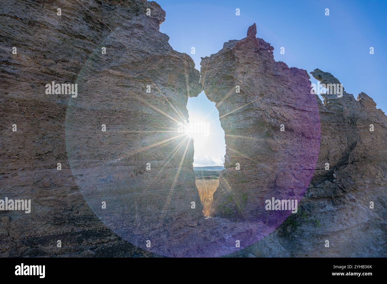 Spettacolari scoppi di sole che penetrano attraverso la formazione rocciosa naturale con motivi di licheni multicolori. Famoso punto panoramico della finestra del tramonto presso l'Isalo National Park Foto Stock