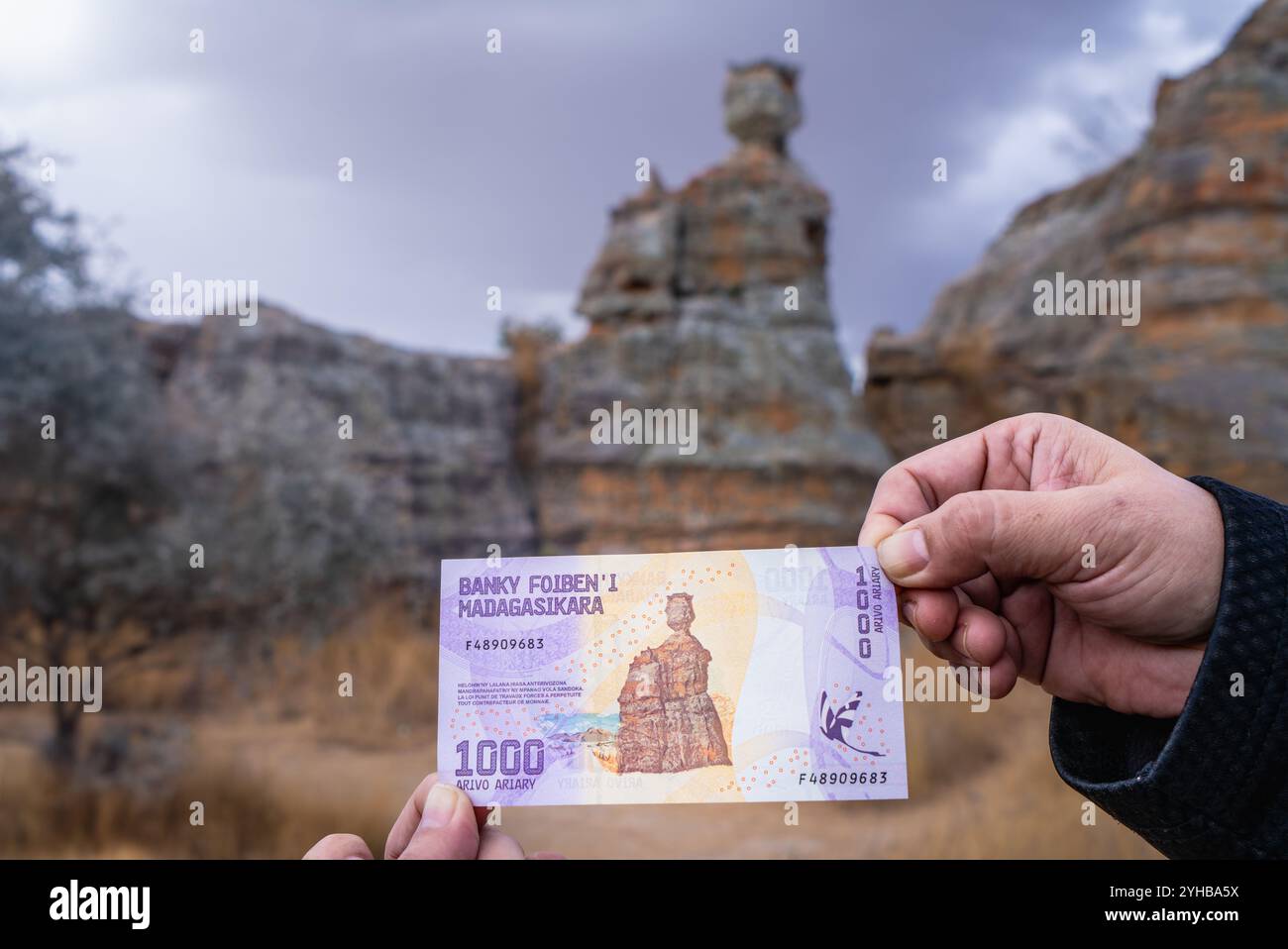 Parco nazionale dell'Isalo, Madagascar - 30 agosto 2024: Mani turistiche che espongono banconote da 1000 Ariary contro la sua ispirazione reale, l'iconica Regina Foto Stock