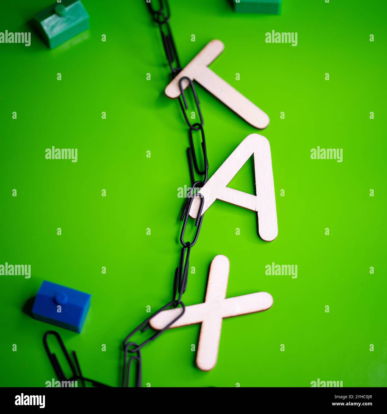 Lettere di legno che scrivono la parola "TASSA" appesa su graffette nere su sfondo verde Foto Stock