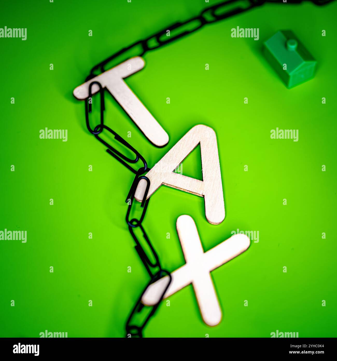 Lettere di legno che scrivono la parola "TASSA" appesa su graffette nere su sfondo verde Foto Stock