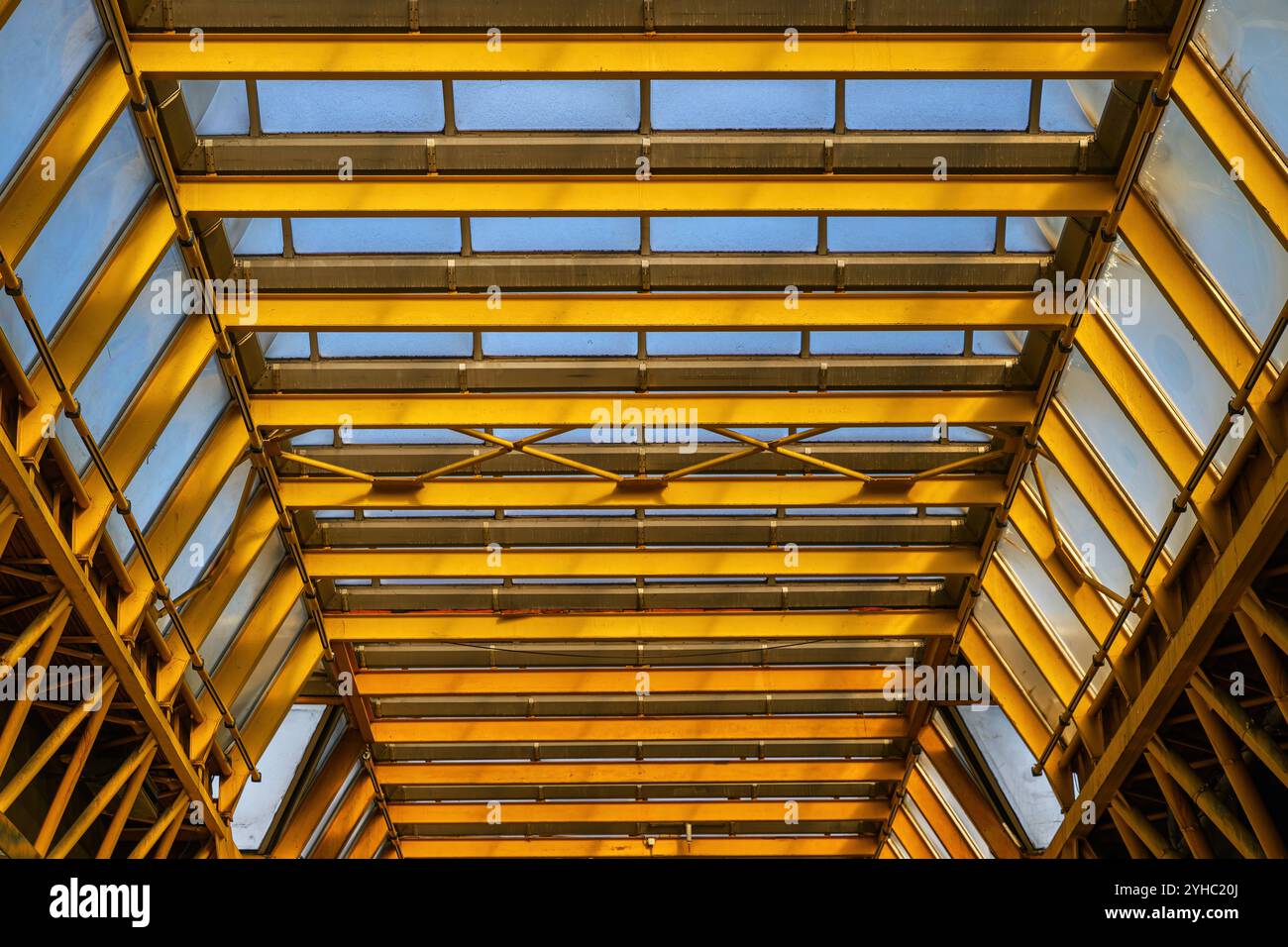 Struttura in metallo giallo del tetto in vetro. Contesto del settore dell'architettura e delle costruzioni. Vista ad angolo basso. Foto Stock