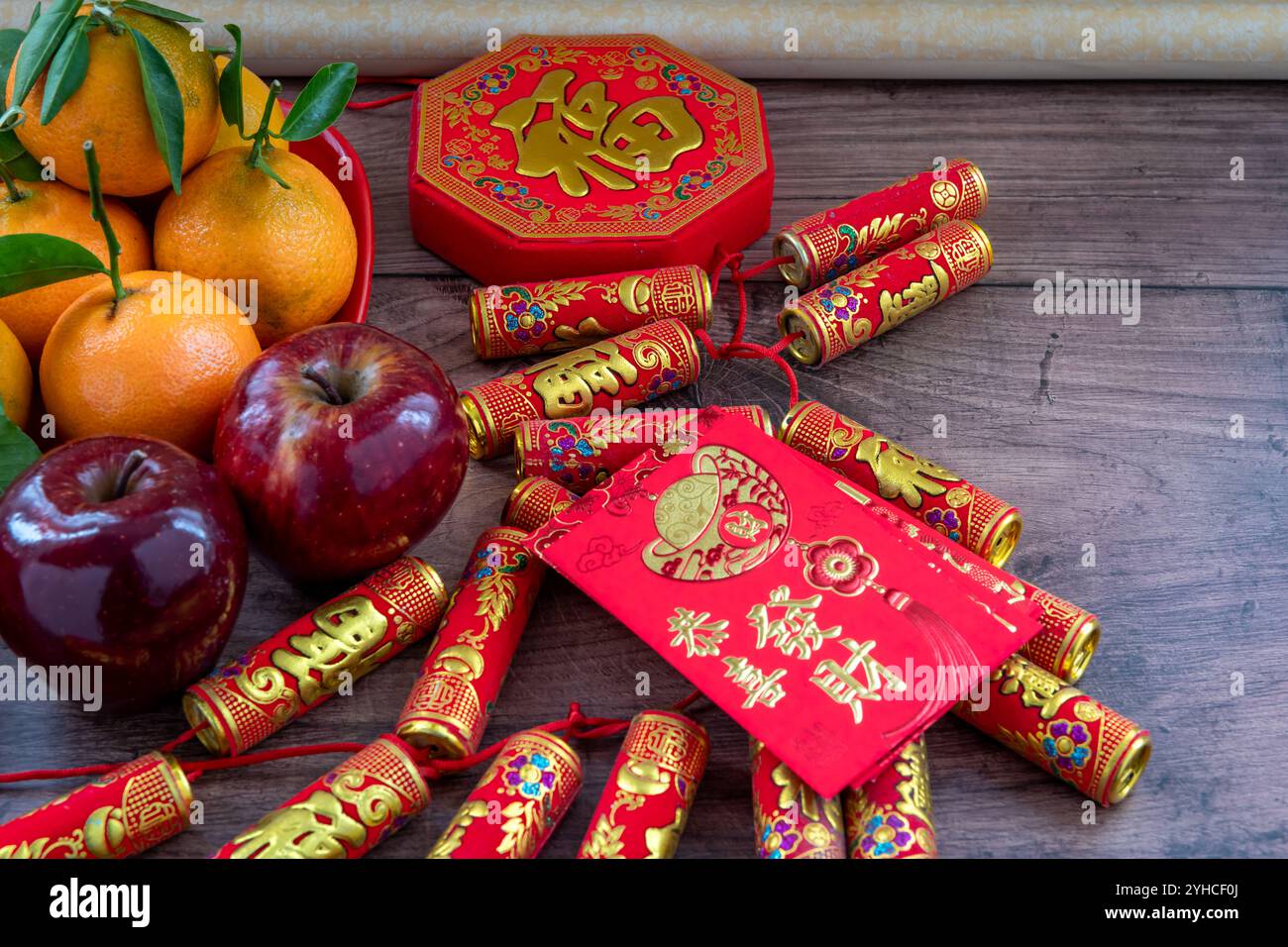 Primo piano di un piatto di mandarini e mele rosse. Decorazioni di Capodanno lunare e pacchetti rossi con buona fortuna, salute, ricchezza parole su di loro. Un Chines Foto Stock