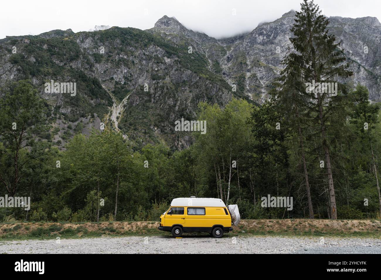 Camper retrò parcheggiato nella foresta con alte montagne sullo sfondo, parco nazionale di Ecrins, Francia Foto Stock