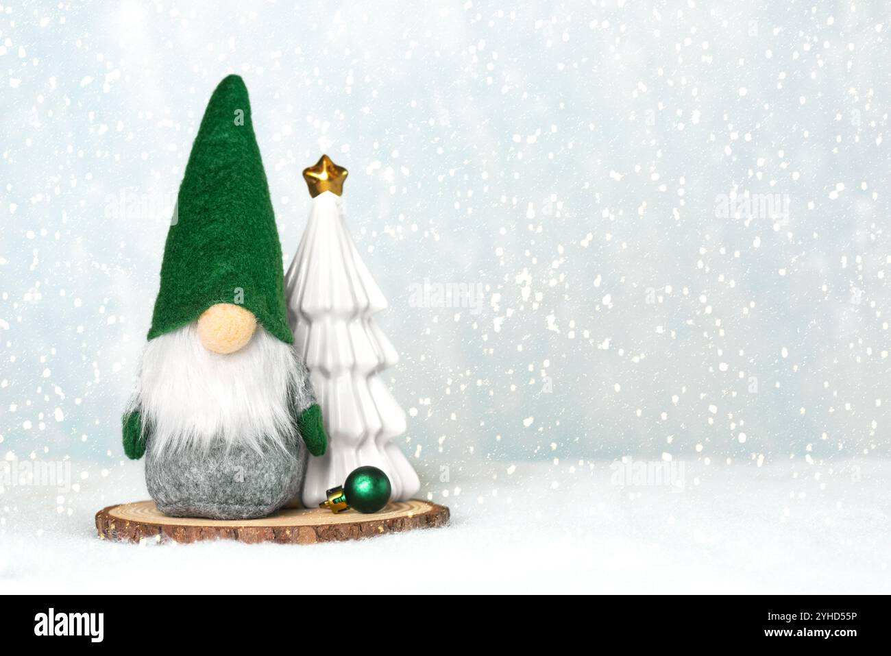 Gnomo natalizio con un albero di natale su una base di legno e fiocchi di neve con spazio per testo sulla neve. Sfondo del concept natalizio Foto Stock