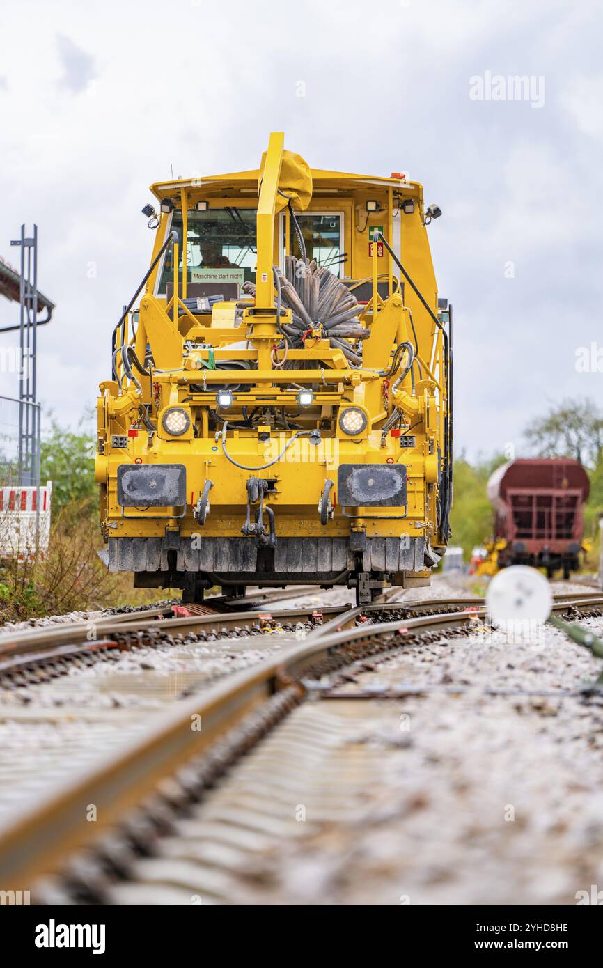 Vista frontale di una grande macchina ferroviaria gialla su rotaie all'aperto, costruzione di binari Hermann Hesse Bahn, quartiere Calw, Foresta Nera, Germania, E. Foto Stock