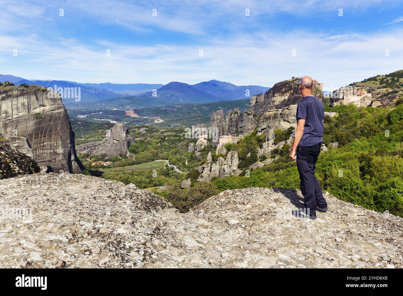 Il turista gode di una vista di eremiti tra alte rocce, monasteri su formazioni di arenaria, Meteora, cielo blu, clima primaverile, Tessaglia, Grecia, Europa Foto Stock