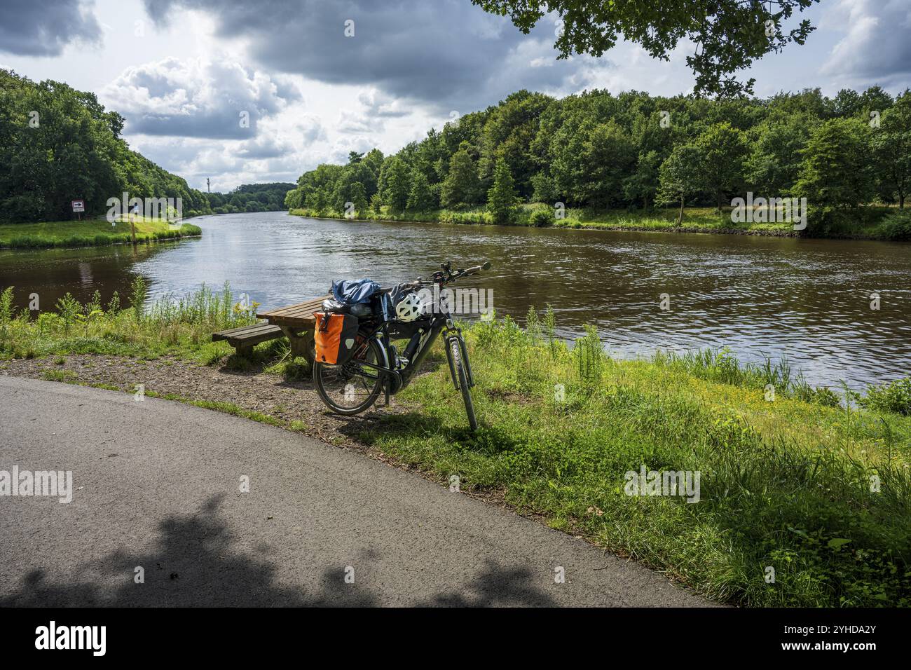Una bicicletta si trova su una pista ciclabile accanto a un tranquillo fiume nella natura, ed è un tour in bicicletta lungo l'EMS e l'Emsaltarm-Roheide Foto Stock