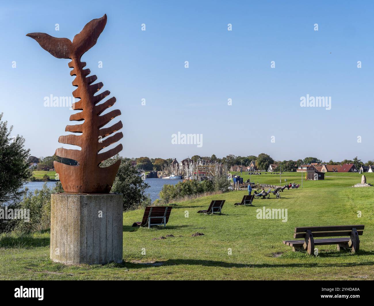 Scultura a spina di pesce, scheletro di pesce dell'artista Joachim Roederer al Leybucht e sullo sfondo gamberetti nel porto di Greetsiel, Gree Foto Stock