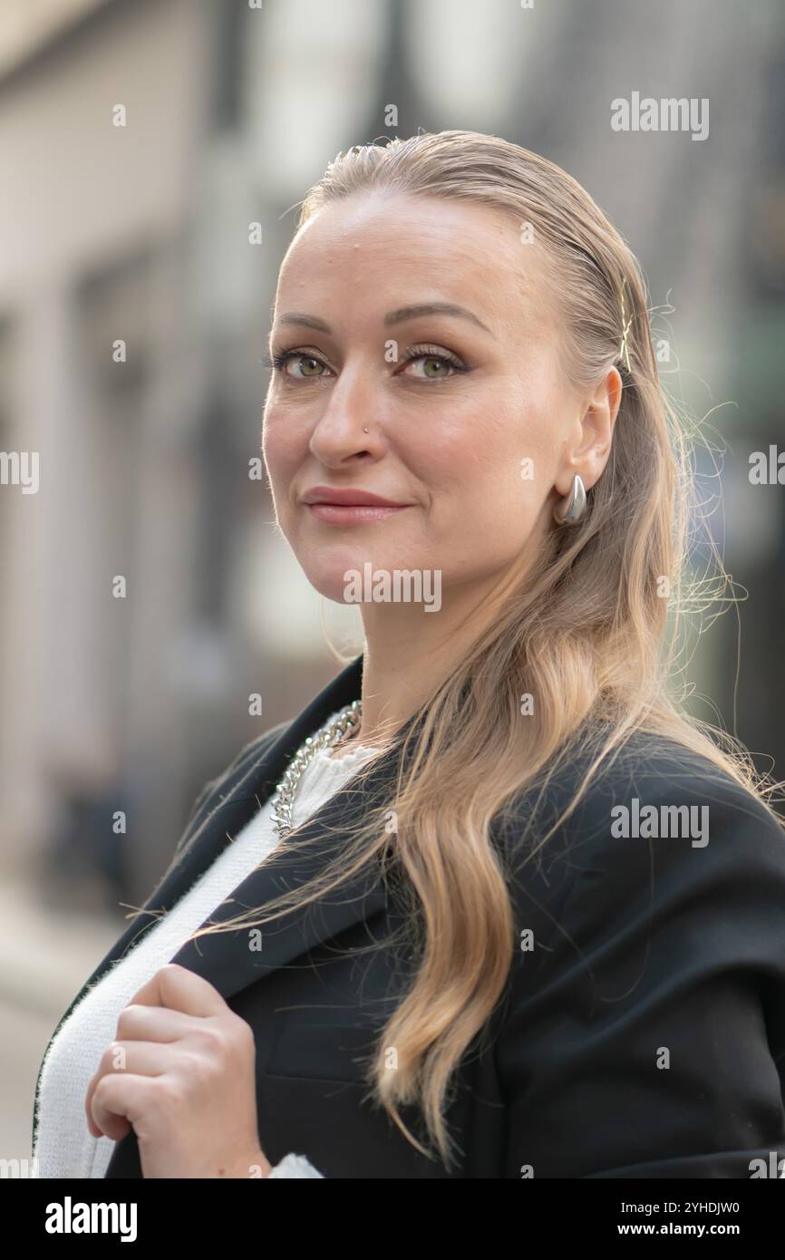 Bella donna dall'aspetto orientale di 35 - 40 anni sullo sfondo di un paesaggio urbano sfocato. Foto Stock