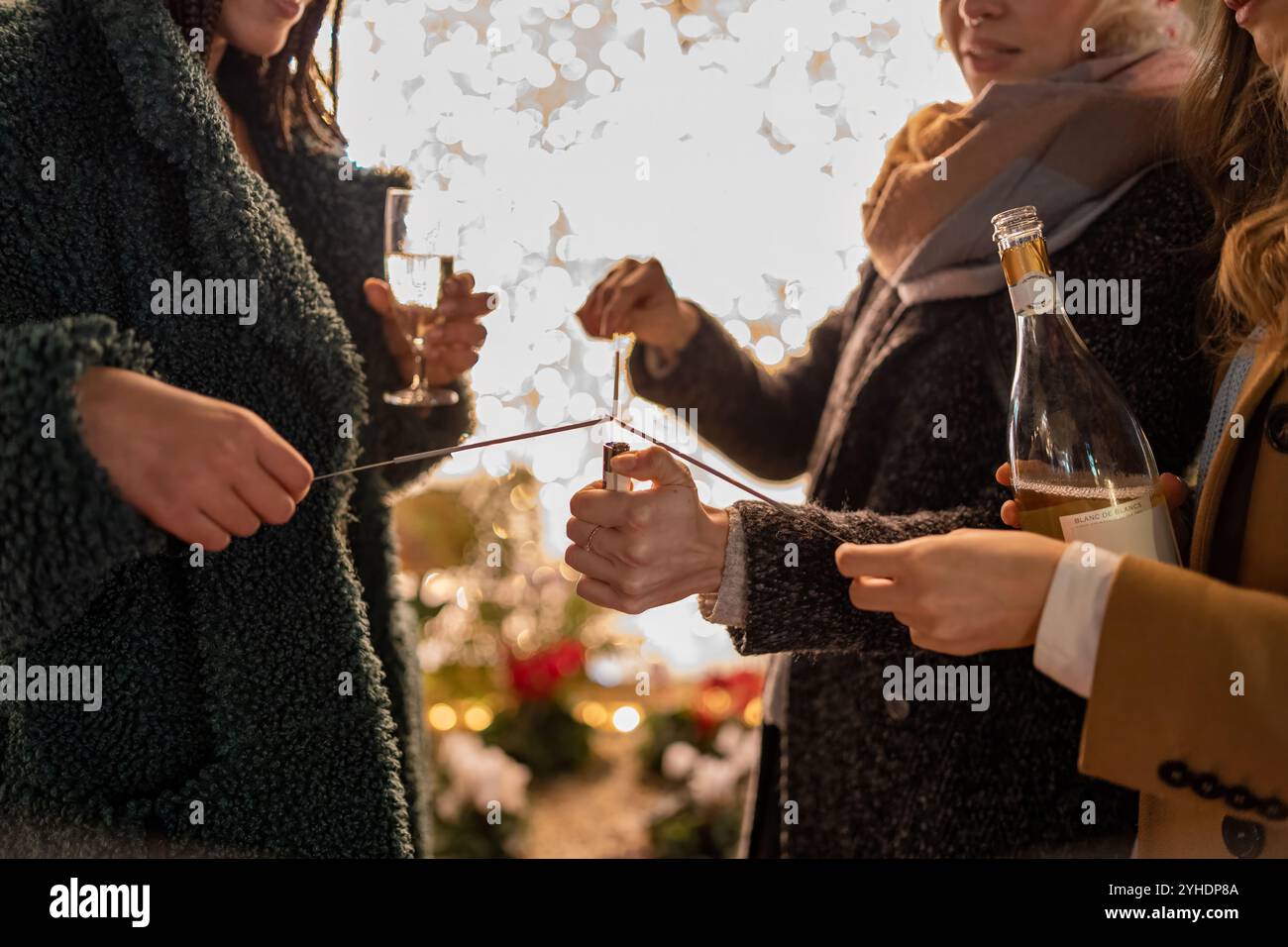 Giovani donne che accendono scintillanti durante i festeggiamenti invernali con champagne, magici momenti serali di festa Foto Stock