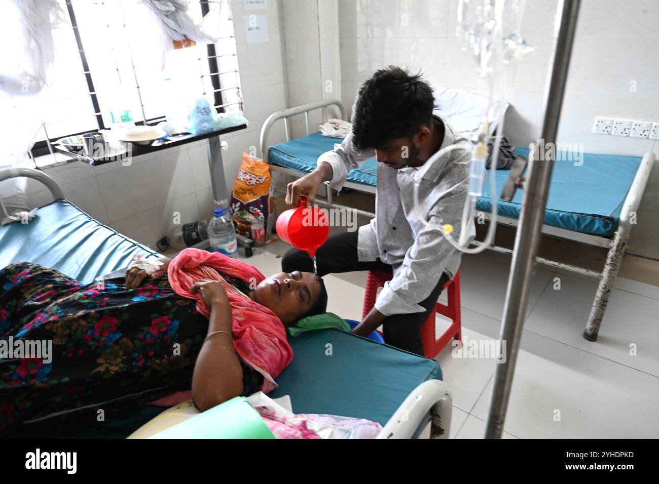 Dacca, Bangladesh. 11 novembre 2024. Un parente versa acqua sulla testa di un paziente affetto da dengue che soffre di febbre dengue riposa all'interno dell'ospedale "Shaheed Suhrawardy" Medical collega di Dhaka, Bangladesh, l'11 novembre 2024. Dal 1° gennaio 2024 all'11 novembre 2024, un totale di 75.142 persone sono state colpite dalla dengue. Almeno 310 persone sono morte nel peggiore focolaio di dengue del Bangladesh mai registrato, hanno detto i funzionari l'11 novembre, mentre gli ospedali sovraccarichi lottano per curare migliaia di pazienti. Crediti: Mamunur Rashid/Alamy Live News Foto Stock