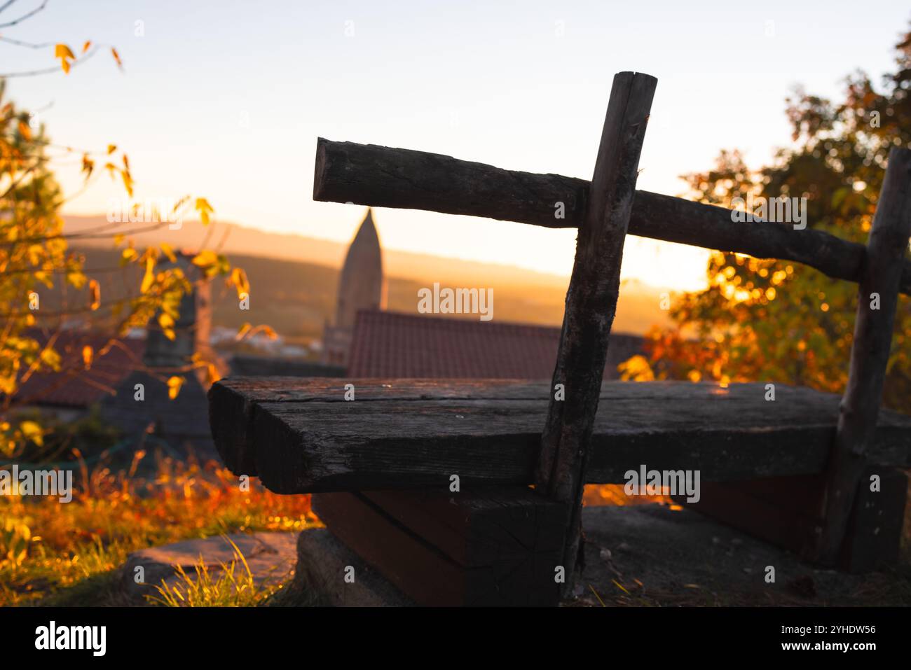Banco rustico che si affaccia su un villaggio al tramonto Foto Stock