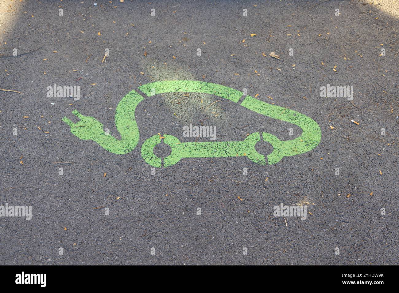 Simbolo verde di ricarica per auto elettriche su asfalto Foto Stock