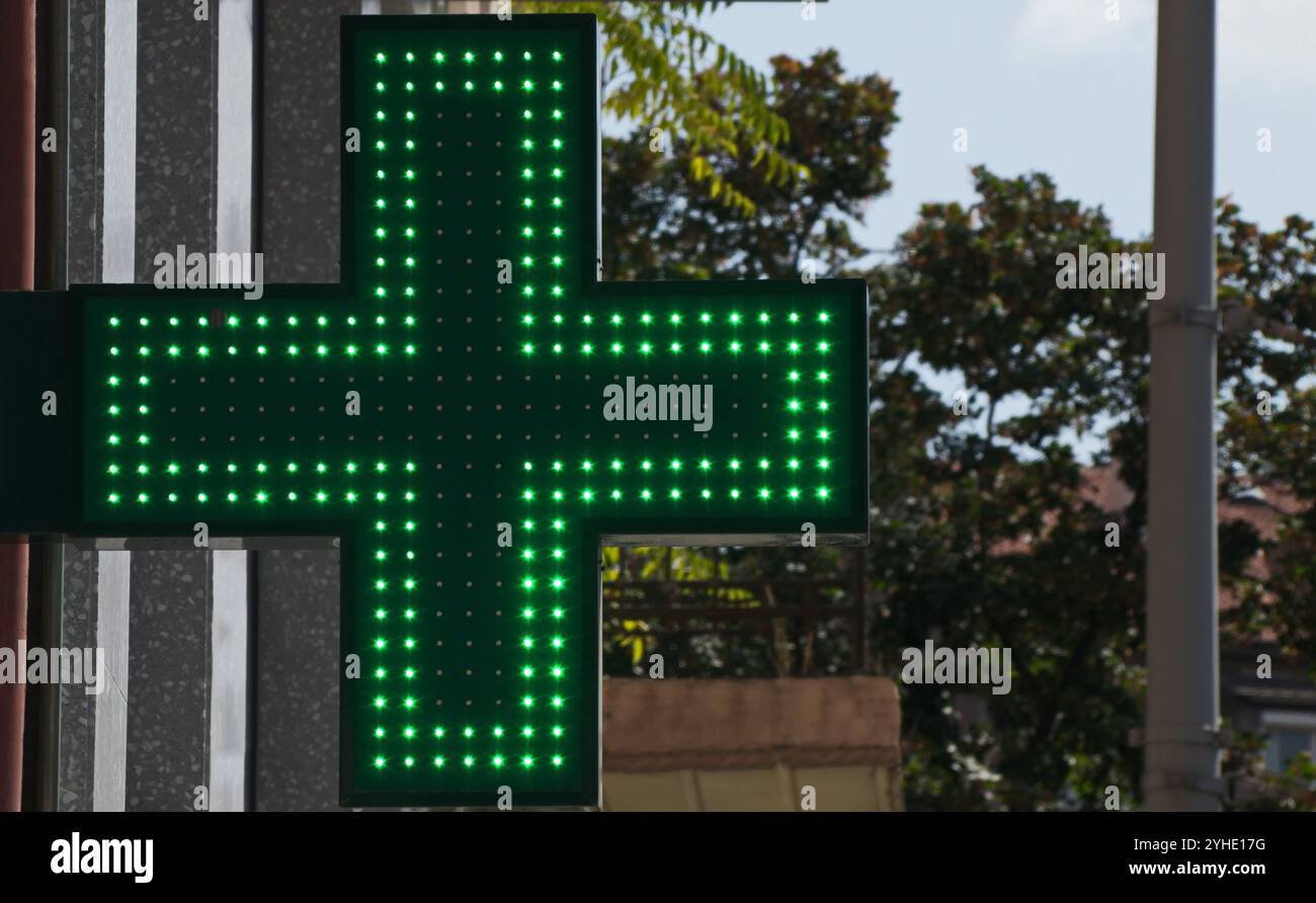 Croce a LED bifacciale pubblicitaria per l'uso esterno e interno da parte di farmacie e altre strutture mediche, emettendo una luce verde brillante Foto Stock