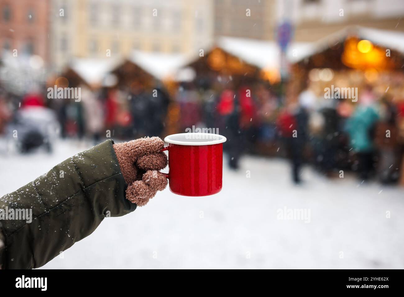 Donna che gusta il VIN brulé o il punch della bevanda calda nella tazza rossa al tradizionale mercato di Natale Foto Stock