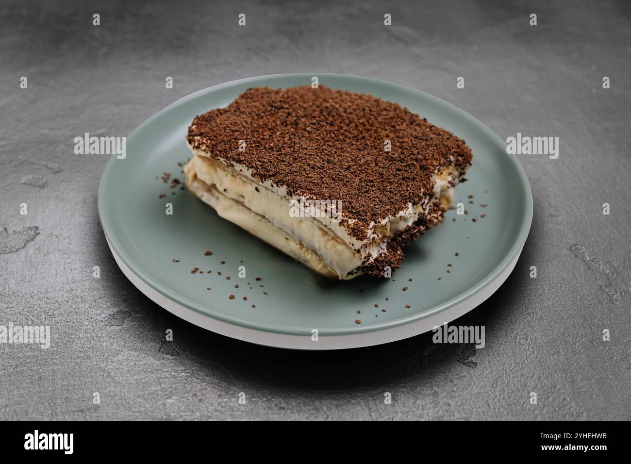 Classico dessert tiramisù con cacao servito su un piatto verde, perfetto per qualsiasi dolce amante Foto Stock