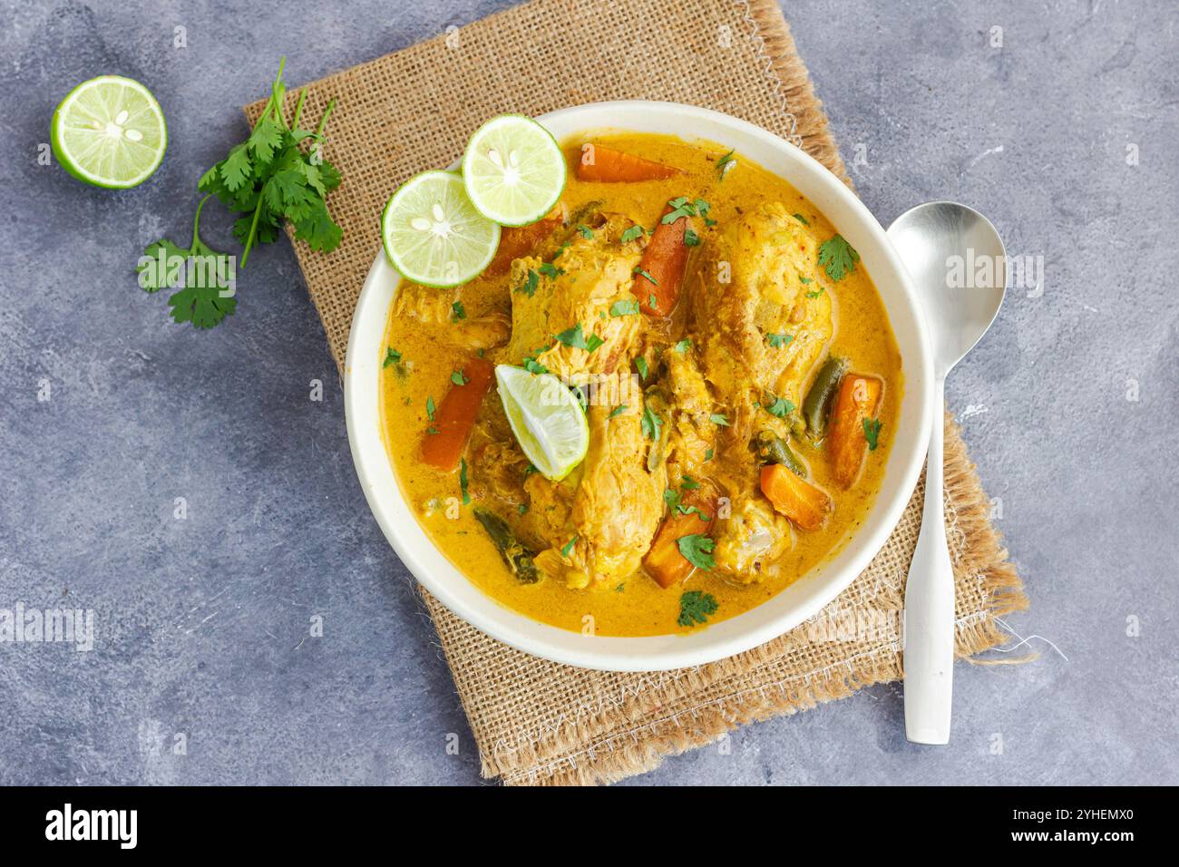 Stufato di pollo sano con latte di cocco guarnito con coriandolo fresco e limone Top Down cibo sano foto Foto Stock