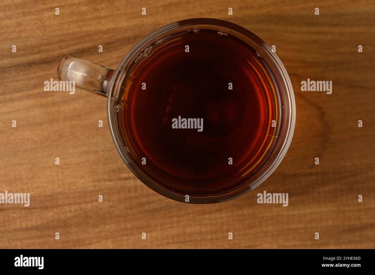 Una tazza fumante di tè nero si trova su una superficie rustica in legno, trasudando un senso di calma alla luce del pomeriggio. Foto Stock