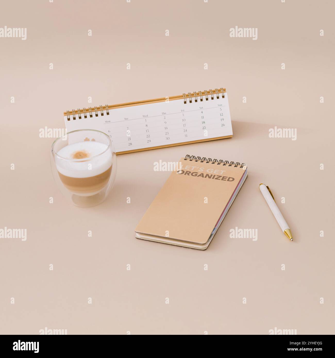 Layout alla moda con calendario, pianificatore, caffè e penna su sfondo beige. Pianificatore per le priorità dell'organizzazione e degli obiettivi. Foto Stock