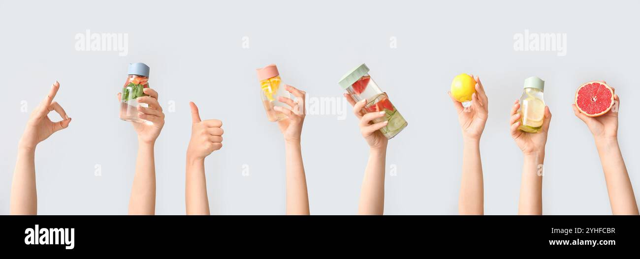 Set di mani che reggono acqua infuso diversa su sfondo chiaro Foto Stock