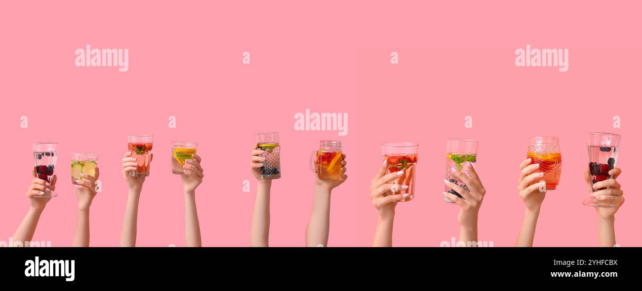 Set di mani che reggono acqua infuso diversa su sfondo rosa Foto Stock
