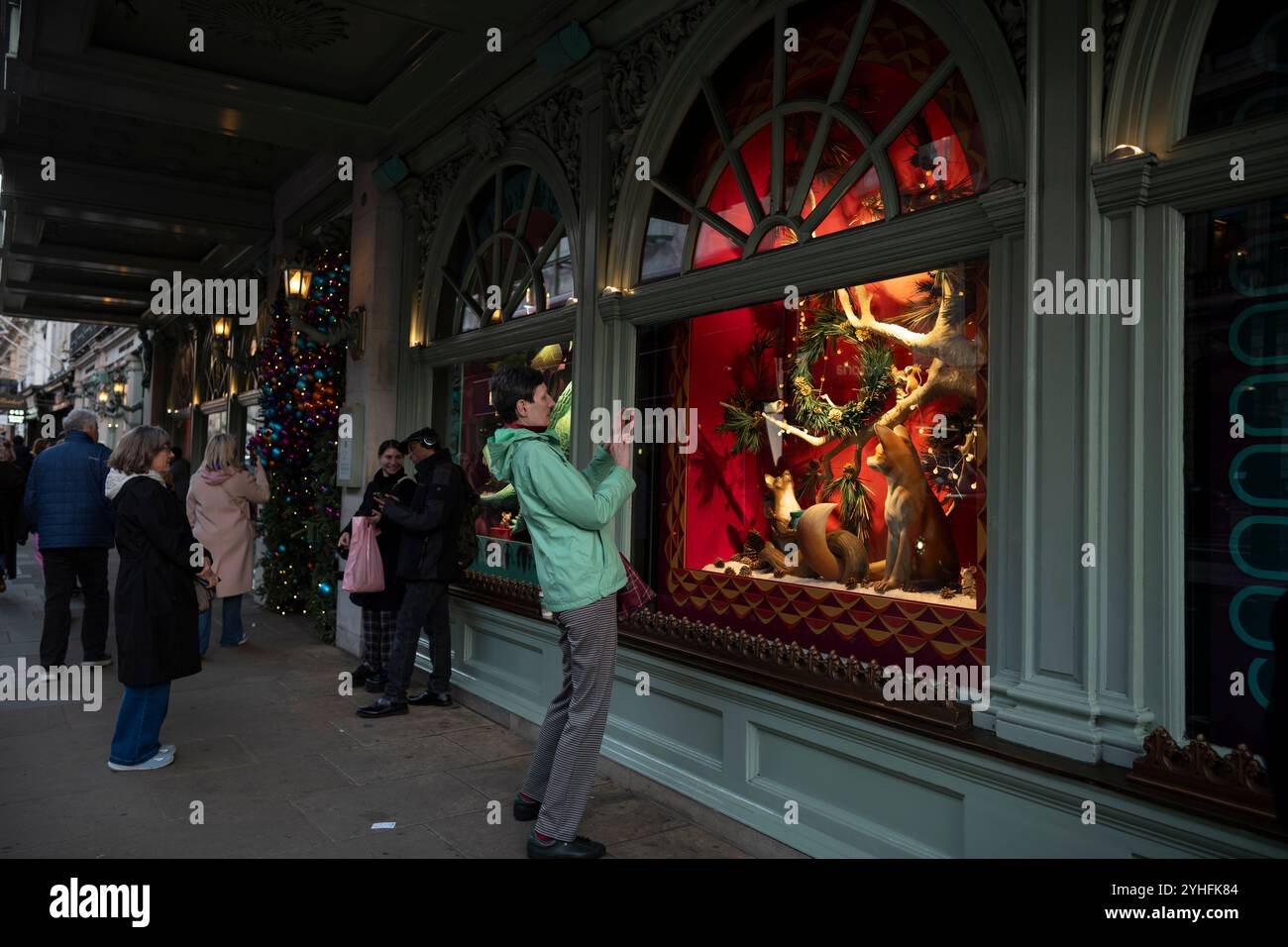 I turisti si radunano intorno alla vetrina Fortnum & Mason Christmas 2024, situata a Piccadilly, Mayfair, nel cuore di Londra, Inghilterra, Regno Unito Foto Stock