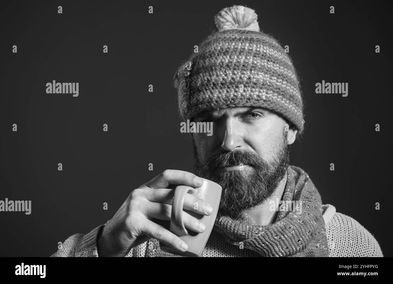 Pausa caffè. Uomo barbuto con tazza di caffè o tè nel caffè. Uomo serio in maglione, cappello e sciarpa beve tazza di caffè o tè. Bel ragazzo informale Foto Stock