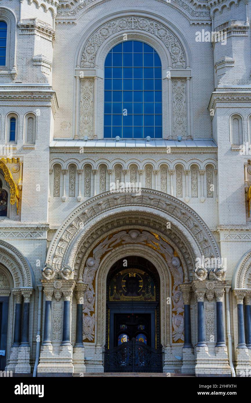 Una vista dettagliata dell'esterno di una cattedrale storica, caratterizzata da una cupola dorata, finestre ad arco e un ingresso ornato sotto un cielo azzurro limpido, che mostra Foto Stock