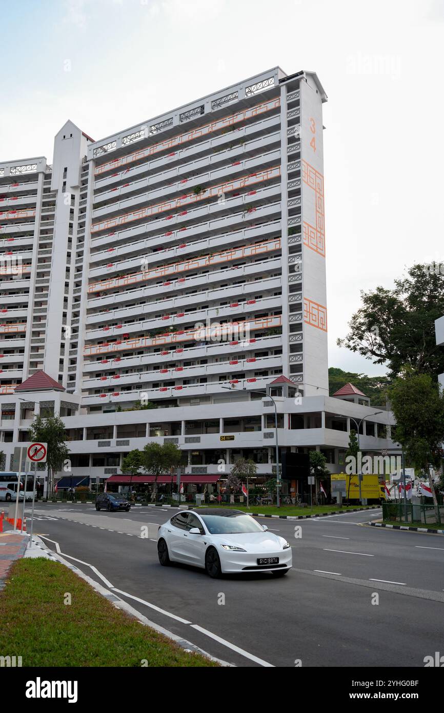 Traversa superiore Singapore, blocco 34 sviluppo abitativo nell'area centrale di Singapore. In primo piano c'è un veicolo elettrico Tesla che segue la strada. Foto Stock