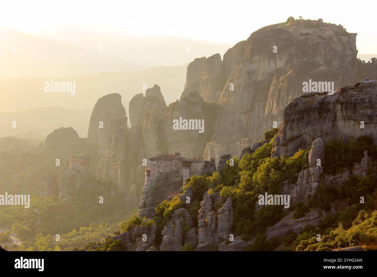 Le splendide formazioni rocciose di Meteora al tramonto, con antichi monasteri arroccati sulla cima delle scogliere circondati da lussureggiante vegetazione e suggestivi paesaggi di montagna Foto Stock