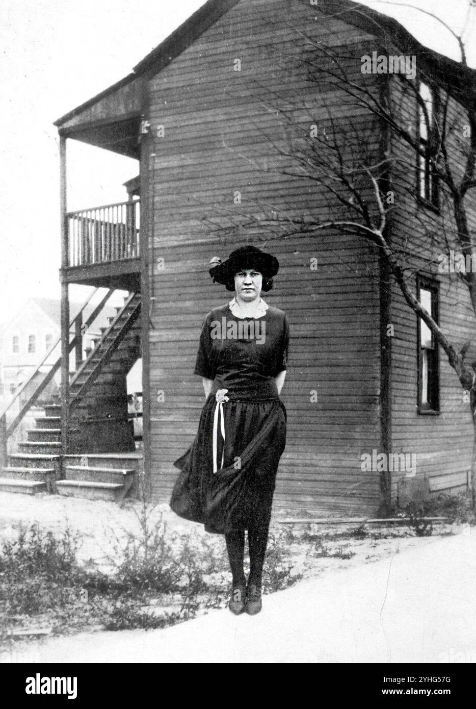 Autentica fotografia d'epoca degli anni '1920 di donna in abito e cappello alla moda all'esterno della casa di legno - rara immagine originale in bianco e nero dello stile americano e dell'architettura dell'inizio del XX secolo Foto Stock Autentica fotografia d'epoca degli anni '1920 di donna in abito e cappello alla moda all'esterno della casa di legno - rara immagine originale in bianco e nero dello stile americano e dell'architettura dell'inizio del XX secolo Foto Stock