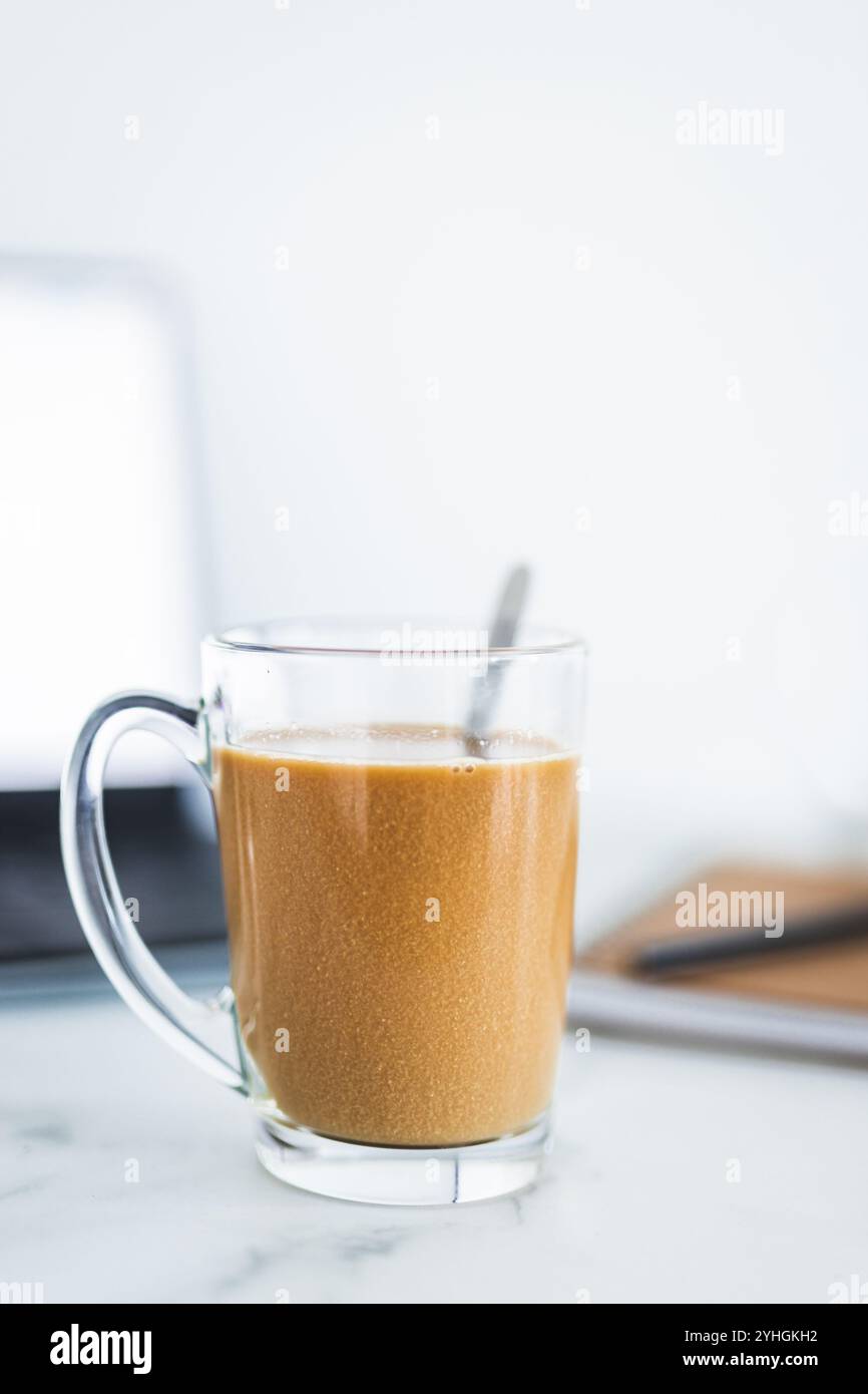 mano che tiene il caffè in una tazza trasparente davanti allo sfondo sfocato degli interni della casa, profondità di campo ridotta, abitudini e concetto di stile di vita Foto Stock mano che tiene il caffè in una tazza trasparente davanti allo sfondo sfocato degli interni della casa, profondità di campo ridotta, abitudini e concetto di stile di vita Foto Stock