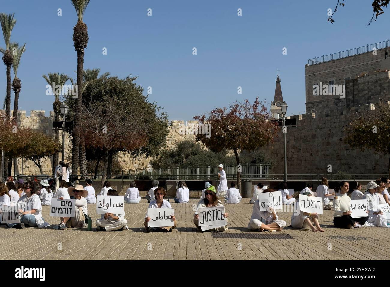 GERUSALEMME - 8 NOVEMBRE: Le attiviste israeliane per la pace vestite con abiti bianchi siedono tranquillamente in un cerchio con segni che promuovono valori di tolleranza e coesistenza durante una manifestazione sit-in davanti alla città vecchia chiedendo un cessate il fuoco e una soluzione diplomatica alla guerra in corso a Gaza e in Libano l'8 novembre 2024 a Gerusalemme. Israele Foto Stock