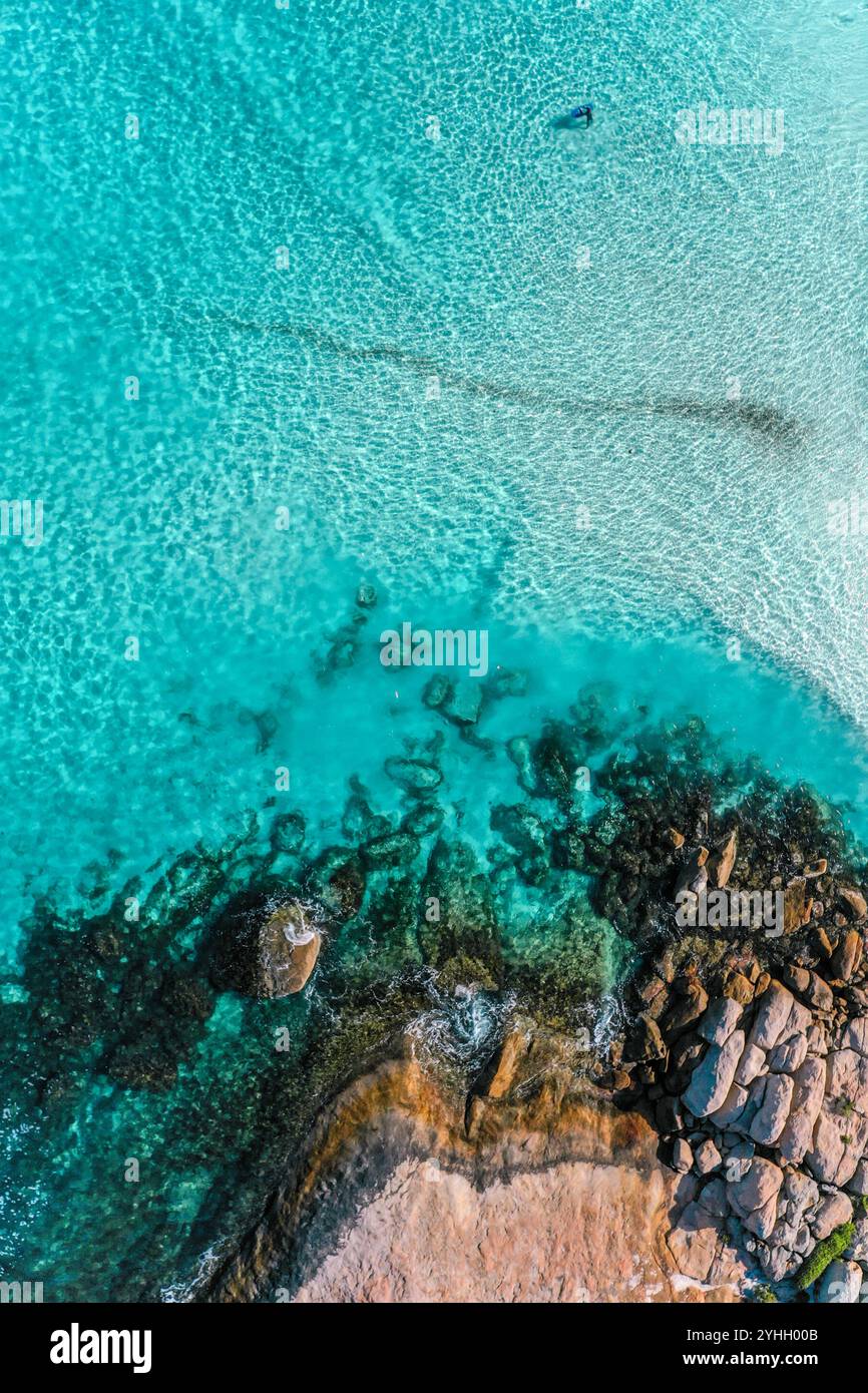 Acque turchesi e coste rocciose, Esperance, Australia Occidentale. Un body boarder attende la prossima onda, con leggere increspature che ballano sulla superficie. Foto Stock