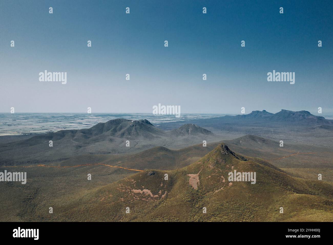 Vista dalla cima del Talyuberlup Peak nelle Stirling Ranges, affacciata sulle altre montagne. Cielo azzurro, flora e fauna verdi. Foto Stock