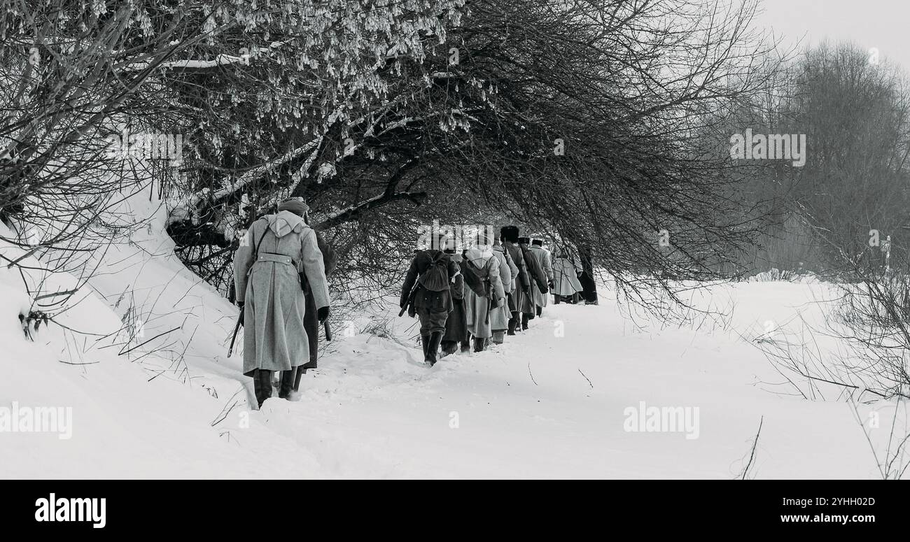 Uomini vestiti da soldati della Guardia Bianca dell'Esercito Imperiale Russo nella marcia della Guerra civile russa attraverso la Foresta invernale innevata. Esercito su Marching. Storico Foto Stock