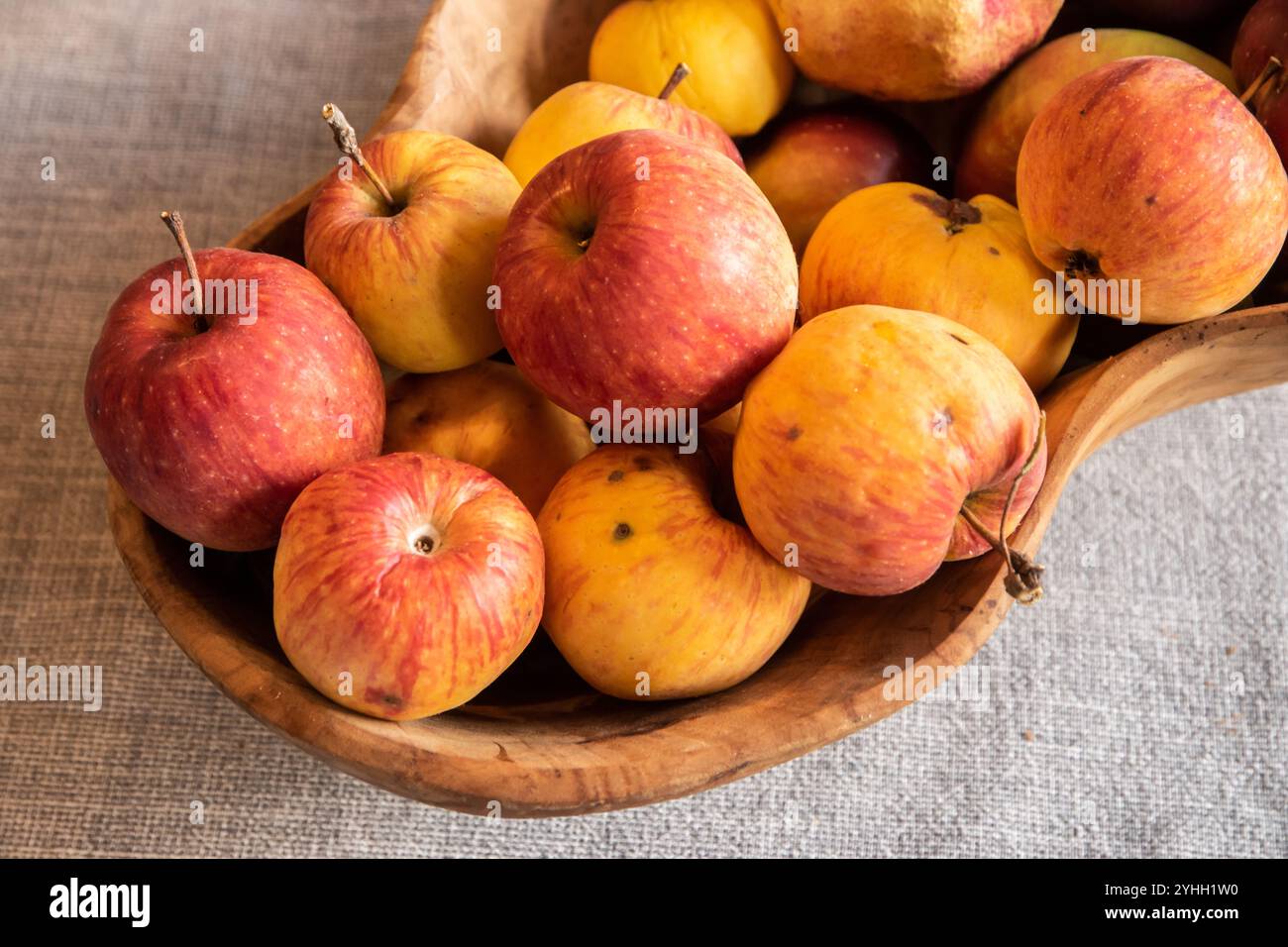 Mele biologiche e melograno in una ciotola di legno su sfondo grigio. Raccolto autunnale. Foto Stock